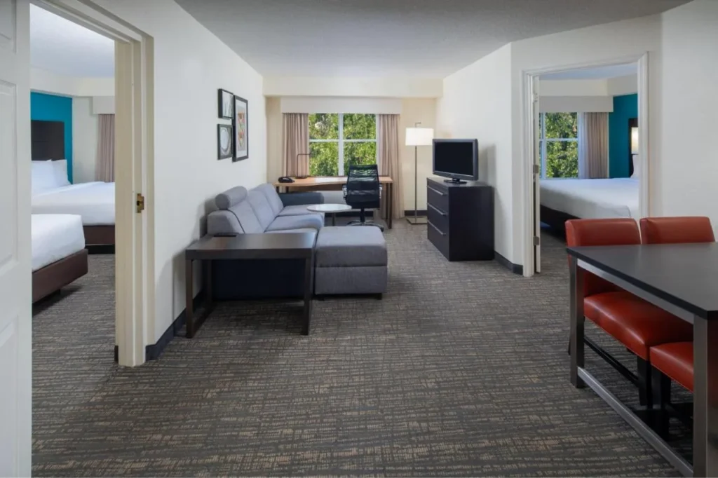 Sala de estar de dos dormitorios con sof&aacute; y mesa de comedor en el Residence Inn Orlando Convention Center