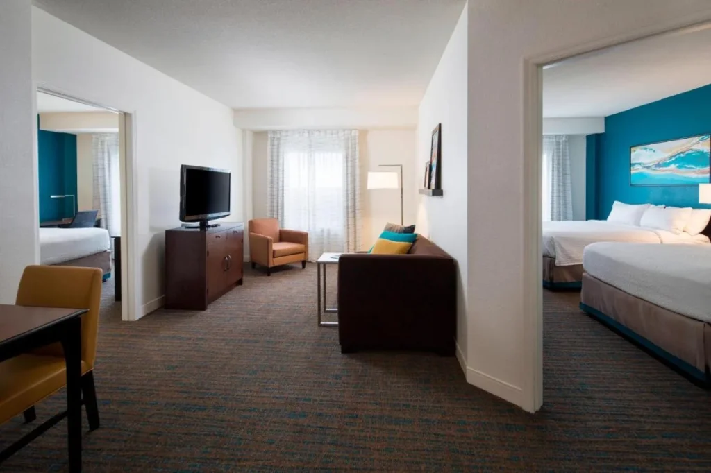 Suite de dos dormitorios con sofá, TV y puertas a ambos dormitorios en Residence Inn SeaWorld