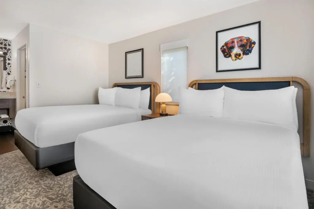 Dos camas debajo de un colorido retrato de perro en Sonesta ES Suites Orlando - Lake Buena Vista