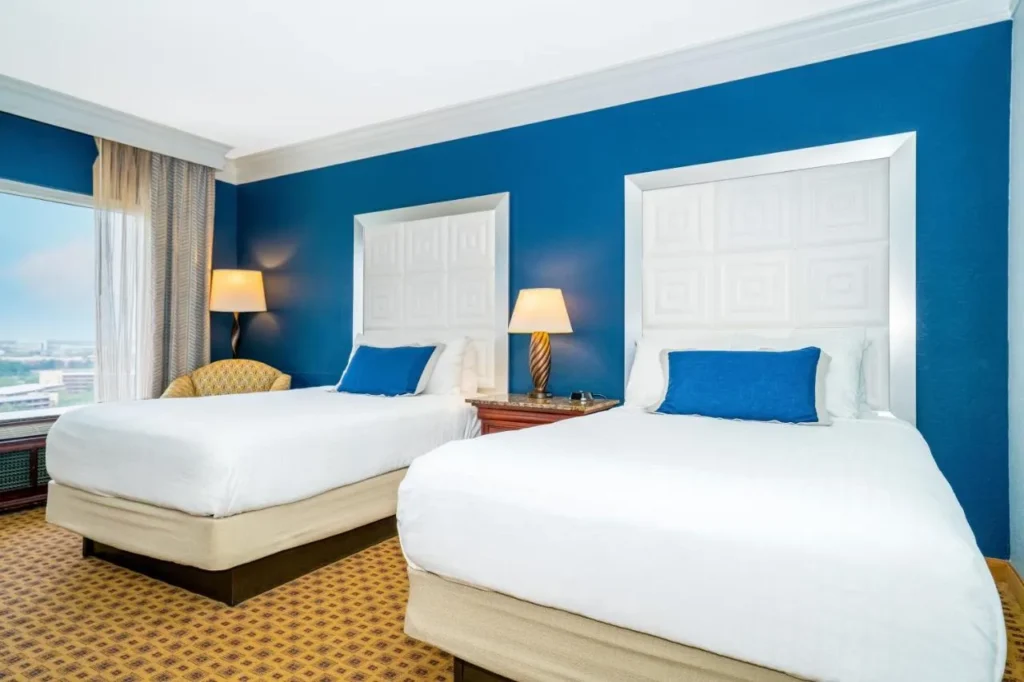 Two beds with navy accent wall and city-view window at Rosen Plaza Hotel