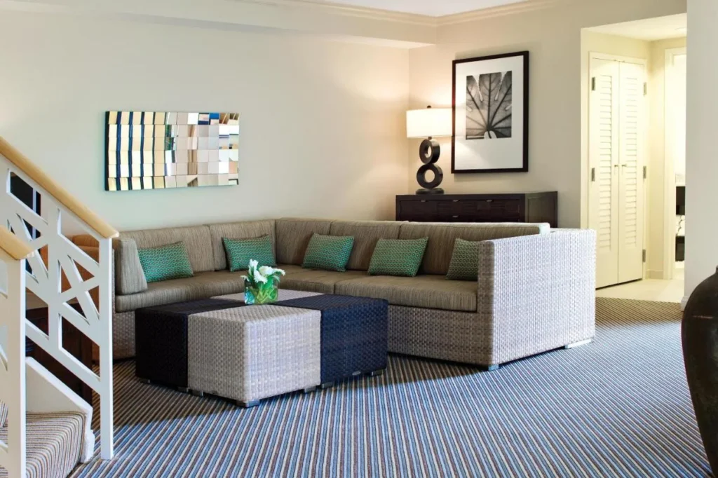 Sala de estar de dos niveles con sof&aacute; en forma de L y escalera blanca en el Hilton Orlando Buena Vista Palace