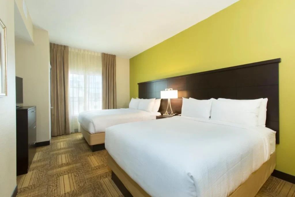 Dos camas queen y una pared decorativa verde en Staybridge Suites Orlando at SeaWorld