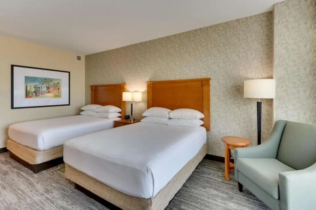 Two queen beds, armchair and Florida postcard art at Drury Inn & Suites near Universal
