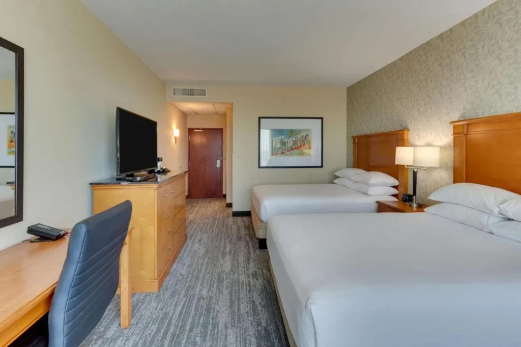 Two queen beds, desk and dresser with TV at Drury Inn & Suites near Universal