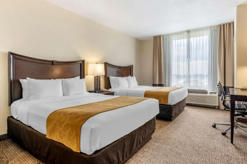 Dos camas queen, escritorio y ventana en una suite en Comfort Suites Maingate East