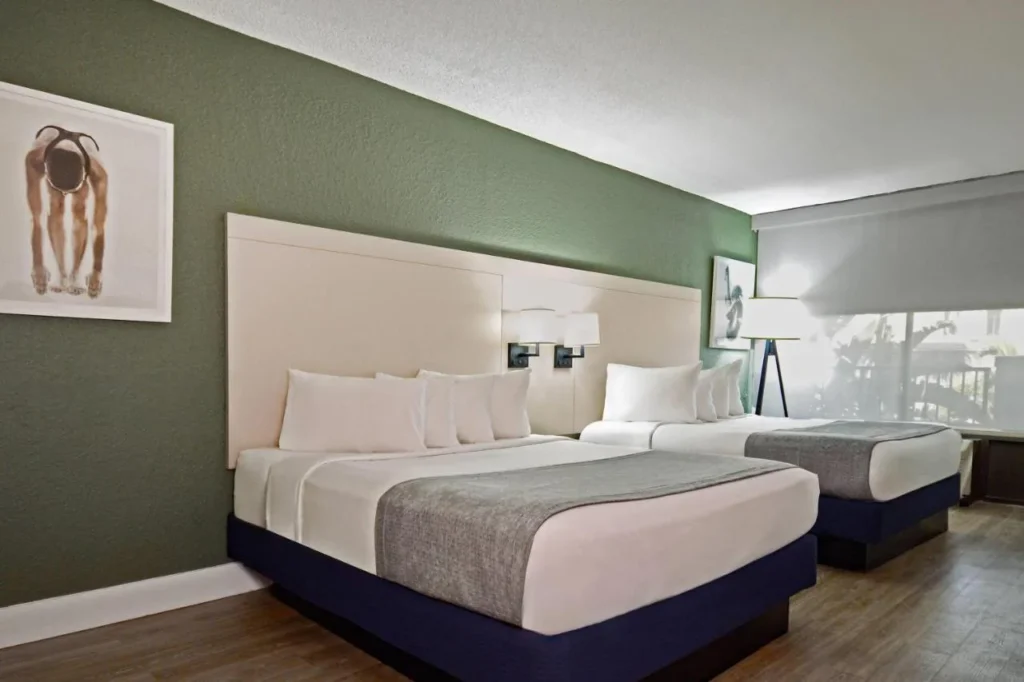 Two queen beds, green accent wall and curtained window in a room at Wyndham I-Drive Avanti