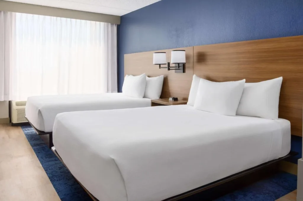 Dos camas queen con ropa de cama blanca y una cabecera de madera en Hyatt Place across from Universal
