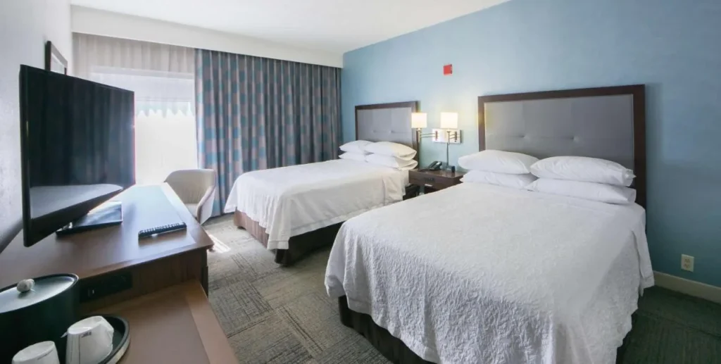 Habitación de dos camas queen en Hampton Inn Lakeland con una pared de acento azul y una gran TV