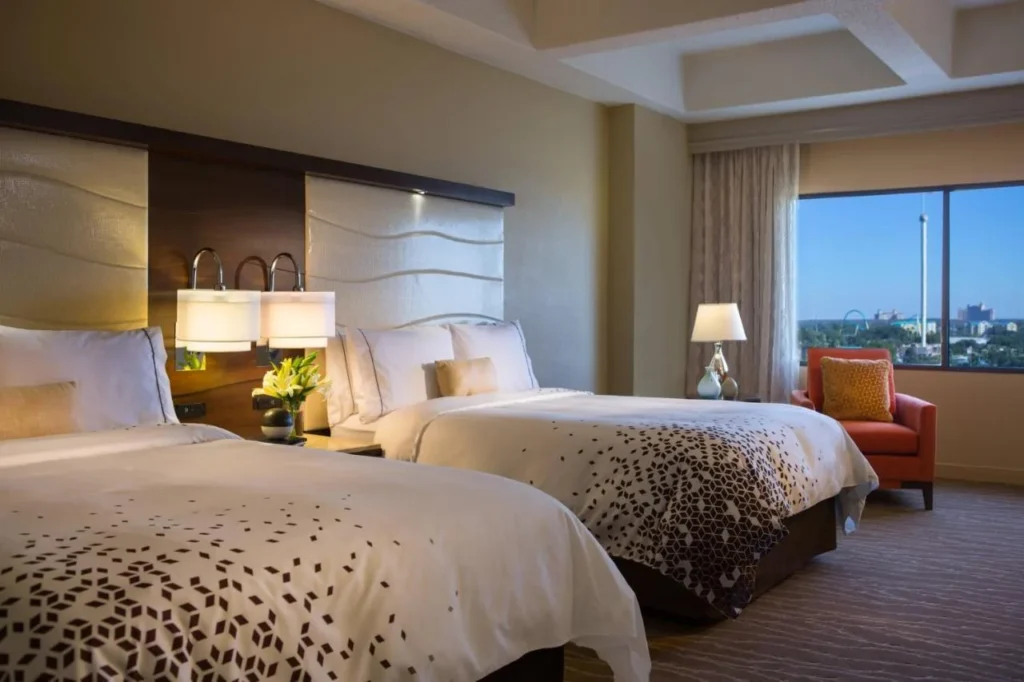 Habitación de dos camas queen en Renaissance Orlando at SeaWorld con un sillón y una ventana frente a SeaWorld