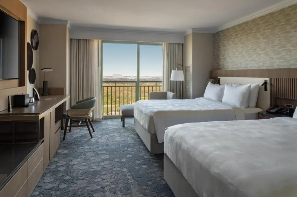 Habitación de dos camas queen con balcón y vistas a los árboles en el JW Marriott Orlando Grande Lakes