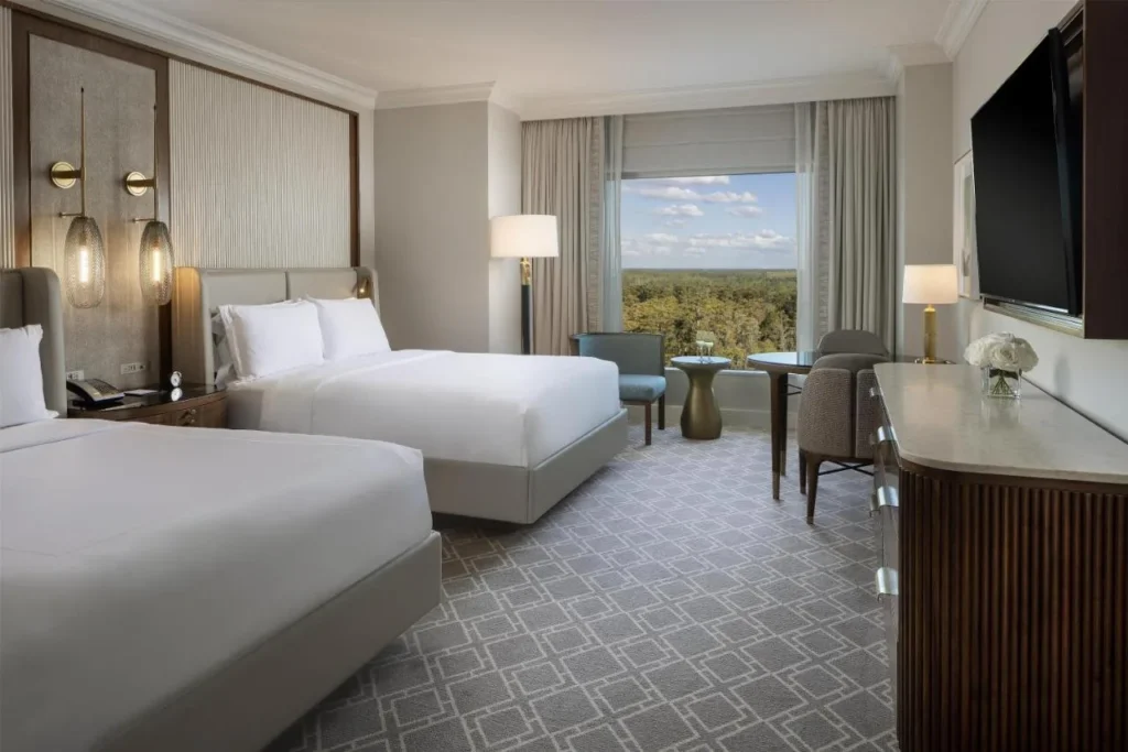 Habitación de invitados de dos camas queen con una amplia ventana sobre las copas de los árboles en Waldorf Astoria Orlando