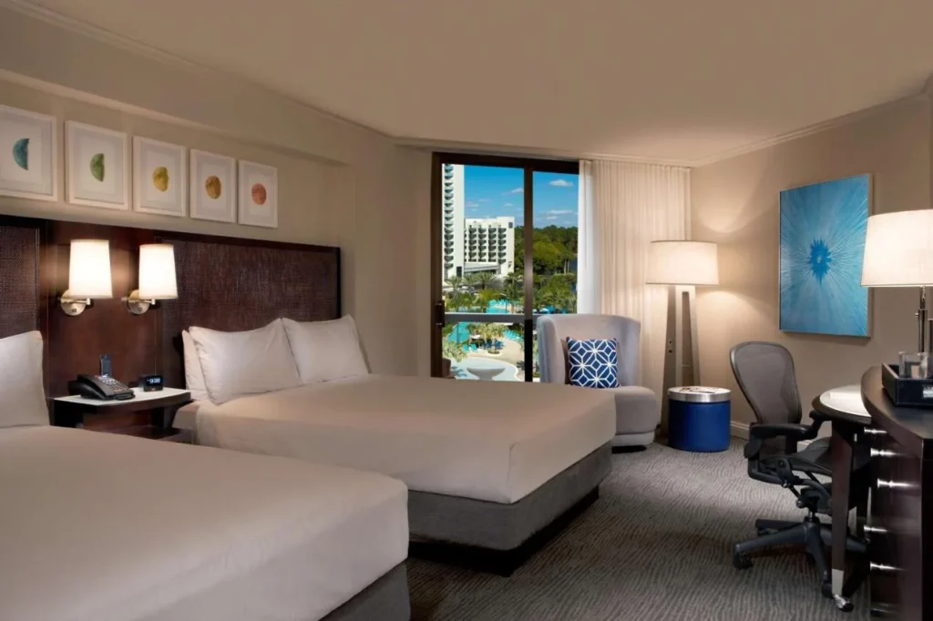 Habitación de dos camas queen con ventana sobre las piscinas del Hilton Orlando Buena Vista Palace