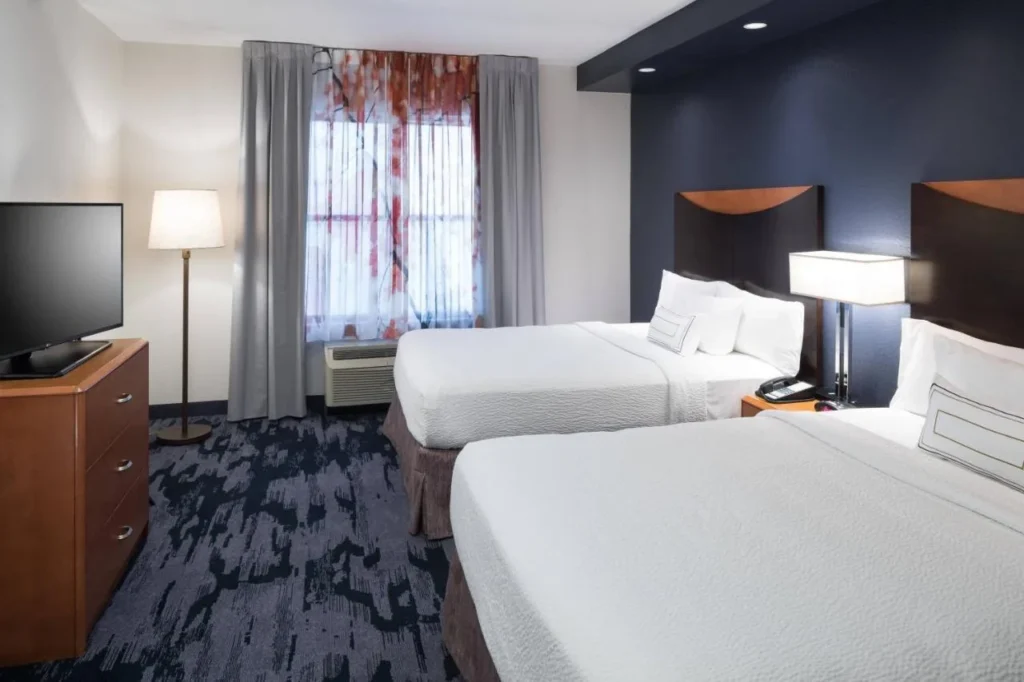 Habitación con dos camas queen, cómoda y televisor en Fairfield Inn & Suites Orlando at SeaWorld