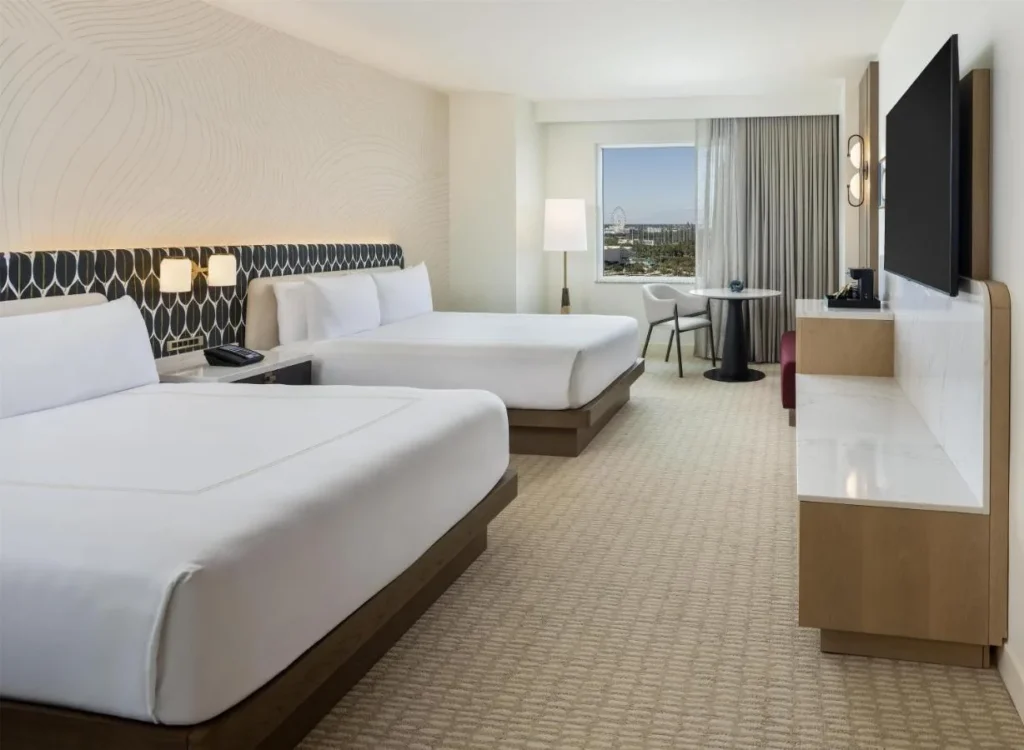Habitación de invitados de dos camas queen con cabeceros estampados y una mesa de ventana en Hilton Orlando