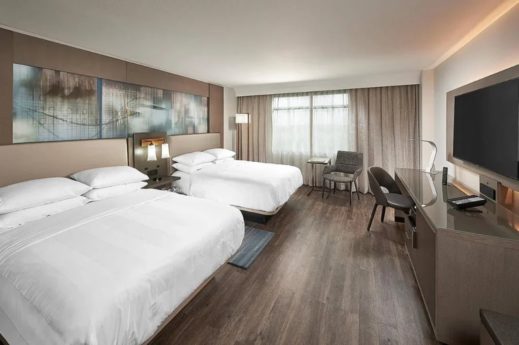 Habitación de dos camas queen con suelo de madera y TV de pared en el Orlando Marriott Lake Mary