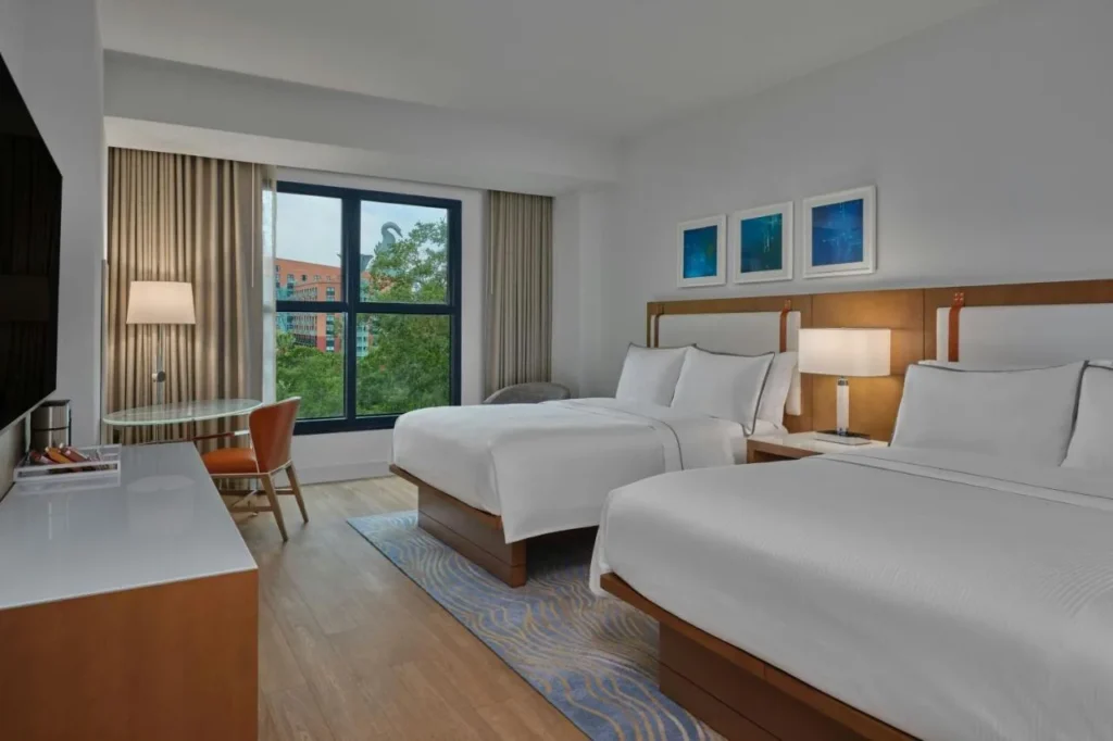 Two-queen guest room with wood-look floor and a window at the Walt Disney World Swan