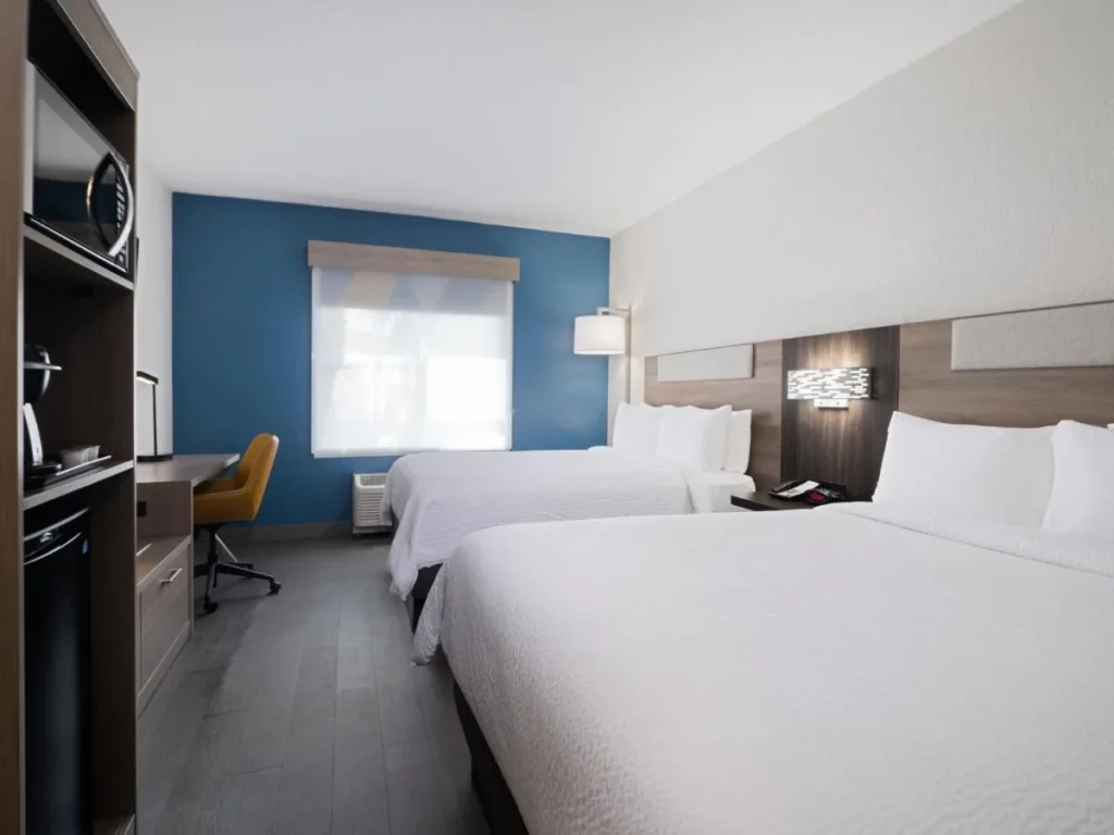 habitación con dos camas queen en Holiday Inn Express Lakeland North I-4 con una pared azul, microondas y escritorio