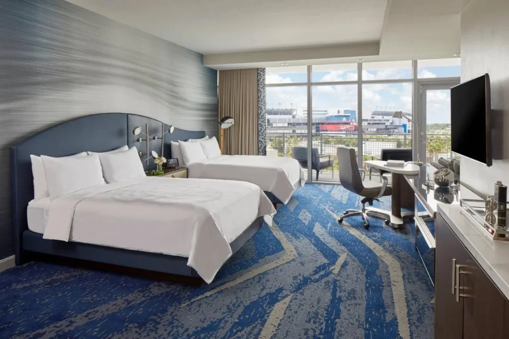 habitación con dos camas queen en el DAYTONA con ventanas de piso a techo con vistas al Daytona International Speedway