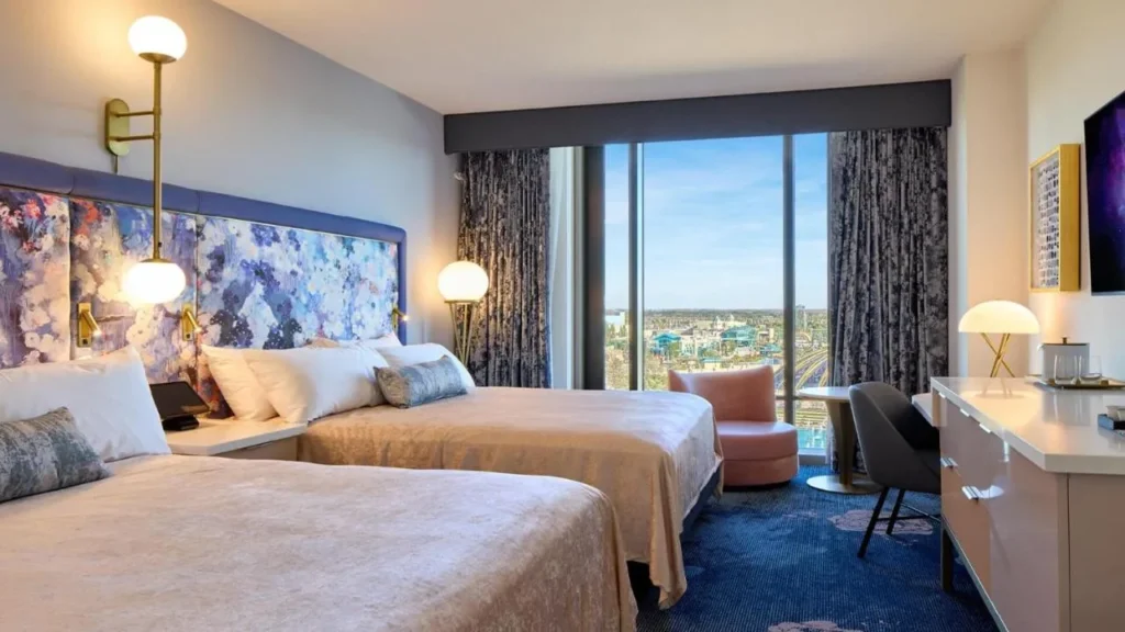 habitación con dos camas queen con cabecera floral, sillón rosa y ventana de piso a techo en Universal Helios Grand Hotel