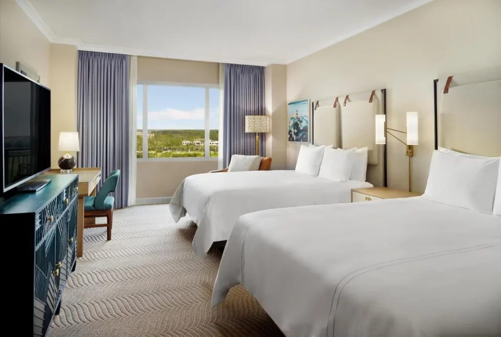 habitación con dos camas queen con una ventana a los jardines verdes en Omni Orlando Resort at ChampionsGate