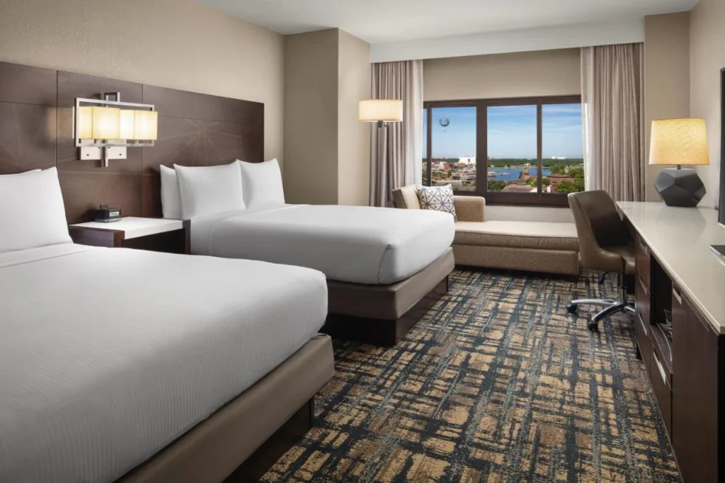 habitación con dos camas queen con chaise y vista a la ventana hacia Disney Springs, Hilton Orlando Lake Buena Vista