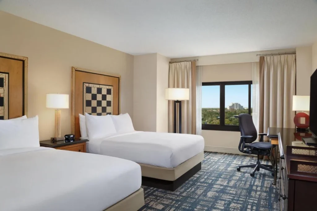Two-queen room with checkerboard headboards and a desk at Hilton Orlando Lake Buena Vista