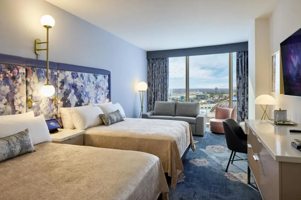 habitación con dos camas queen con cabecera floral, sofá y ventanas altas en Universal Helios Grand Hotel