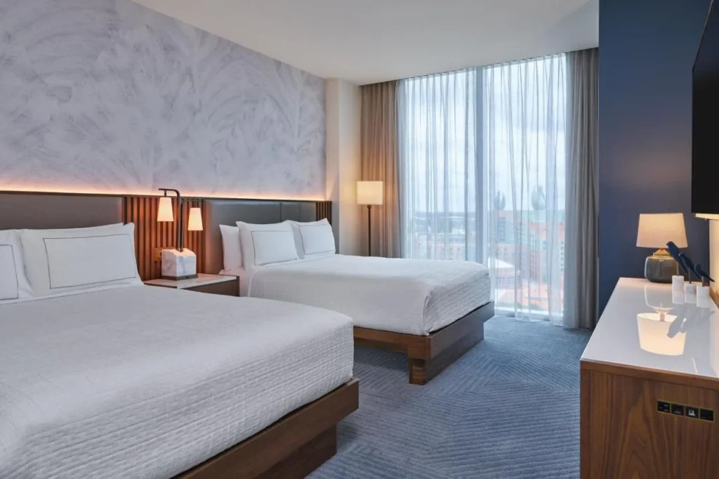 Two-queen room with sheer floor-to-ceiling curtains at Walt Disney World Swan Reserve