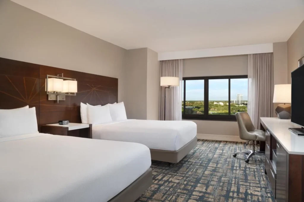 Two-queen room with wood headboards and a window view at Hilton Orlando Lake Buena Vista