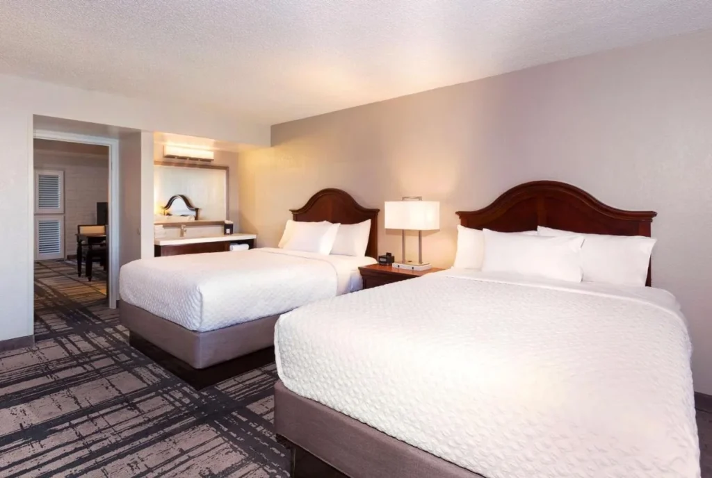 Two-queen suite bedroom with vanity beyond at Embassy Suites Orlando International Drive Convention Center