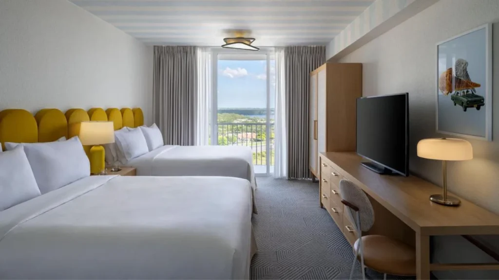 Habitación de dos camas queen con cabeceras amarillas, TV y ventana en Renaissance Orlando Resort