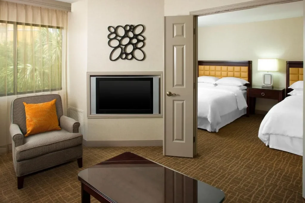 Suite de dos habitaciones con sill&oacute;n, TV y dos camas en el Sheraton Suites Orlando Airport