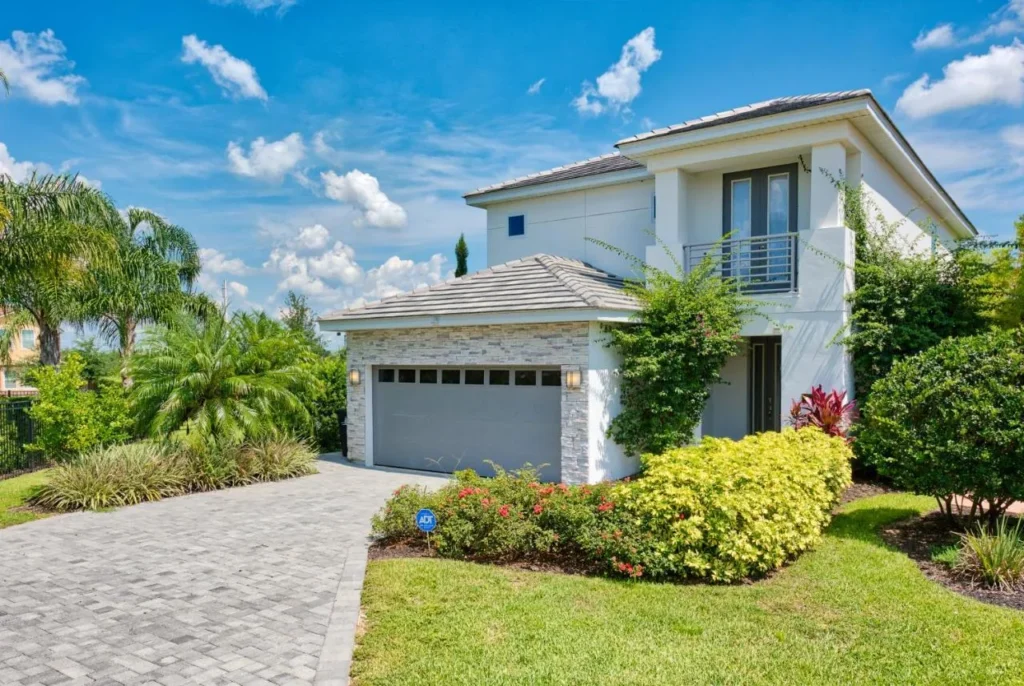Two-story white vacation home with a two-car garage and paver driveway at Encore Resort