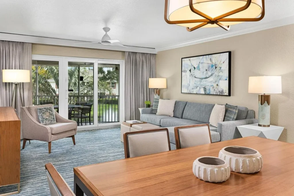 Villa actualizada sala de estar con sofá gris, mesa de comedor y puertas de balcón en Sheraton Vistana Resort
