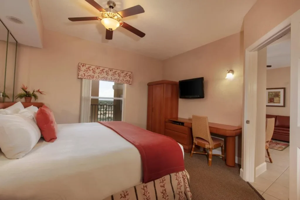 Villa bedroom with large bed, desk, wardrobe and wall TV at Westgate Town Center Resort