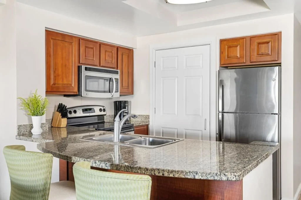 Cocina de la villa con una barra de desayuno de granito, refrigerador de acero inoxidable, estufa y microondas en el Marriott's Grande Vista
