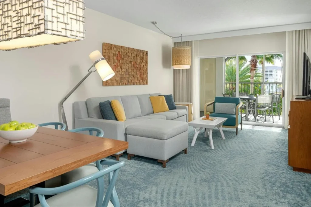 Villa living room with a gray sectional, dining table and balcony at Marriott's Harbour Lake