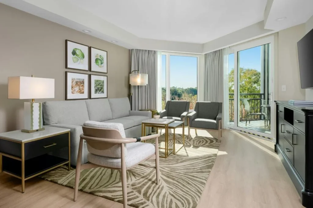 Villa living room with gray sofa, armchairs and balcony doors at Marriott's Royal Palms