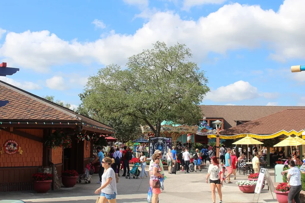 Visitors walking past shops and a shady oak tree in the Marketplace area of Disney Springs