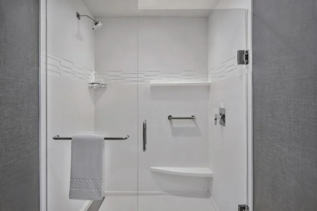 Ducha a ras de suelo con puerta de cristal y banco incorporado en el Residence Inn Flamingo Crossings