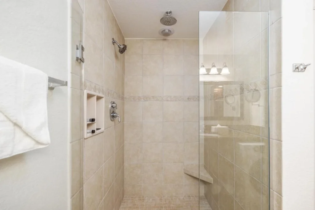 Walk-in tiled shower with glass panel and corner seat in a bathroom at Westgate Vacation Villas