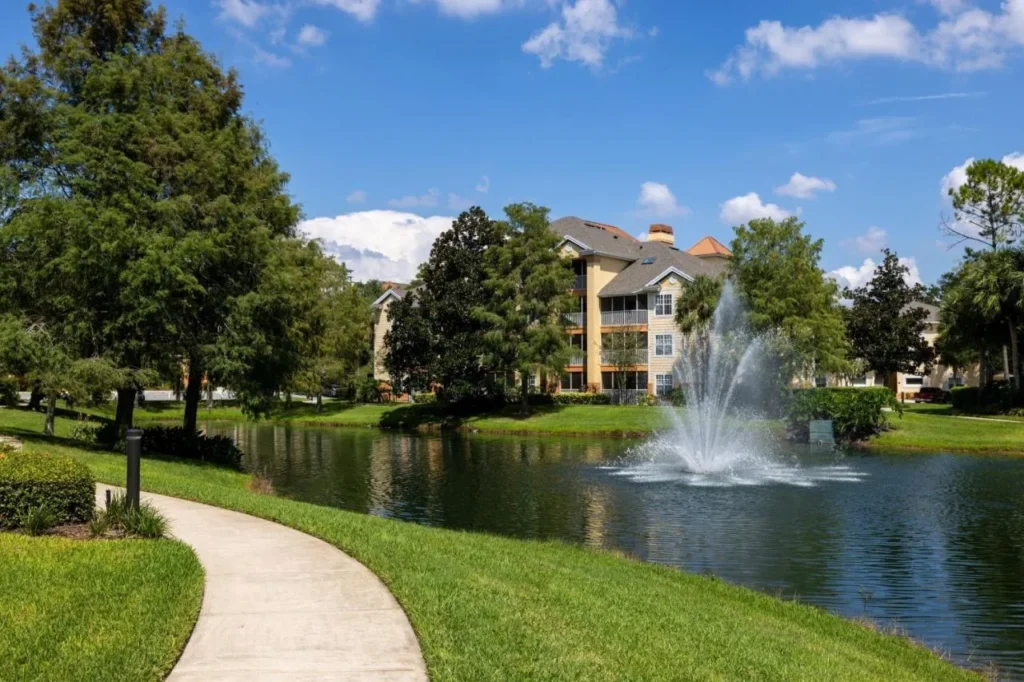 Sendero para caminar al lado de un lago fuente y un edificio de cuatro pisos en Sheraton Vistana Resort Villas