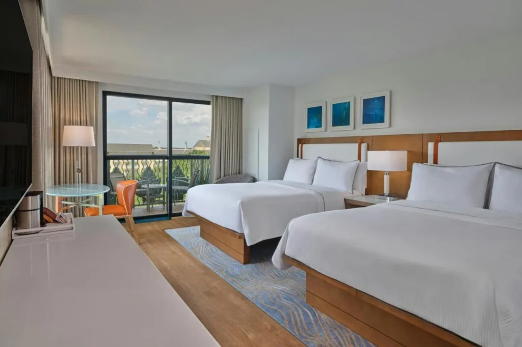 Walt Disney World Swan guest room with two beds, a round table and a balcony door