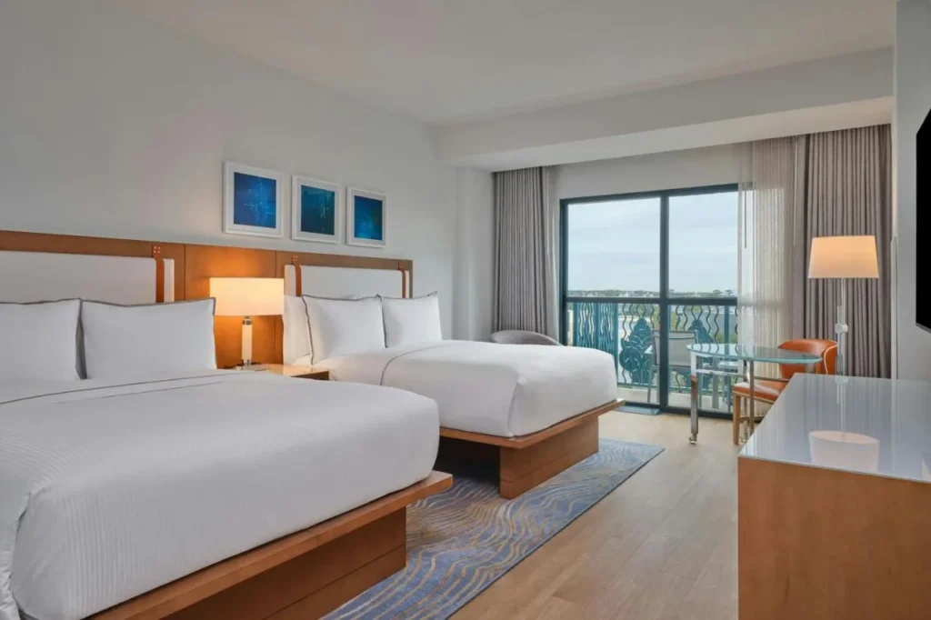 Walt Disney World Swan guest room with two beds, a round table and a balcony door