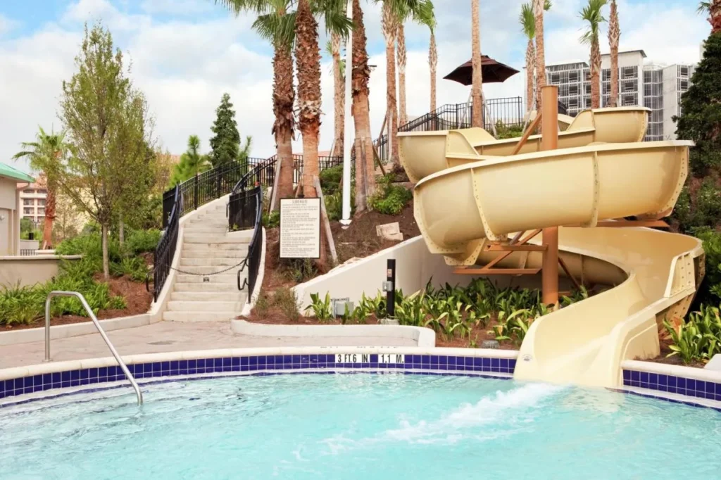 Water slide ending in a pool among palm trees at Signia by Hilton Orlando Bonnet Creek