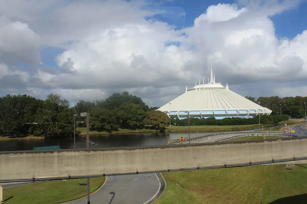 Cono blanco de la montaña espacial en Magic Kingdom visto a través de un lago y una carretera en un día nublado