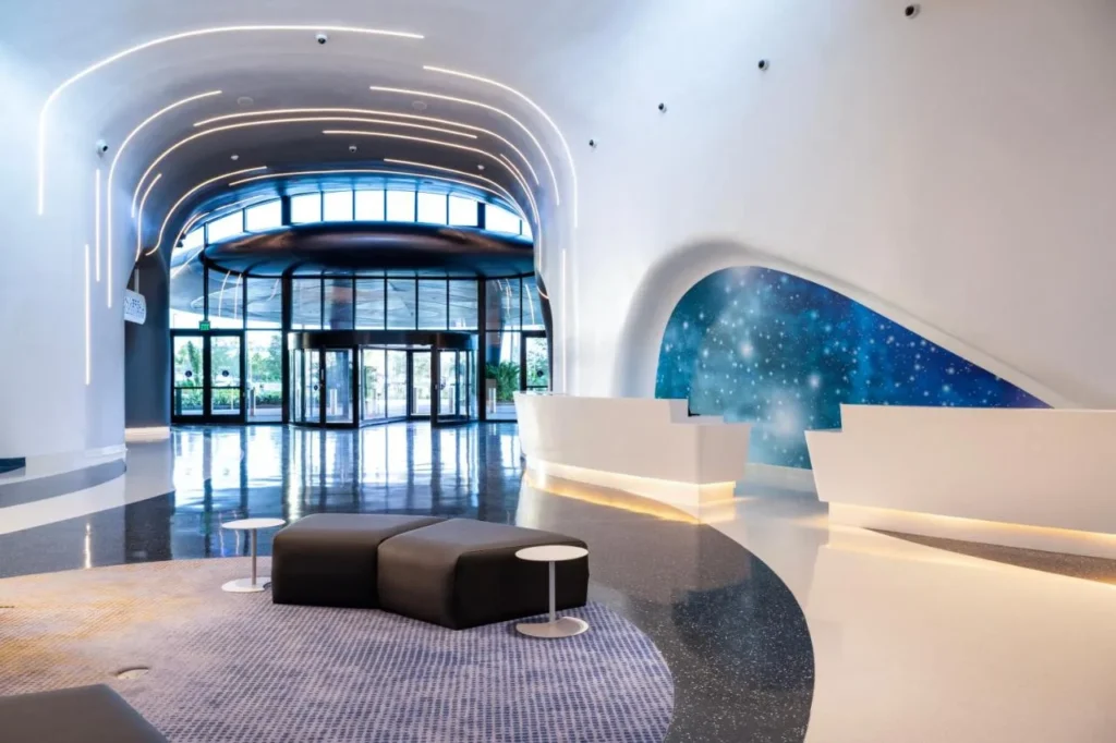Lobby curvo blanco con mostradores de check-in y un mural de galaxia en Universal Stella Nova Resort