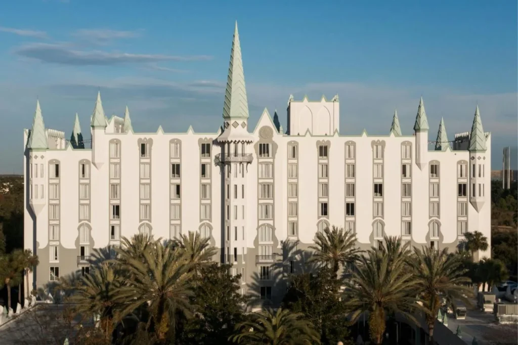 Fachada blanca del hotel Castle con torres y torres de punta verde sobre palmeras en Orlando