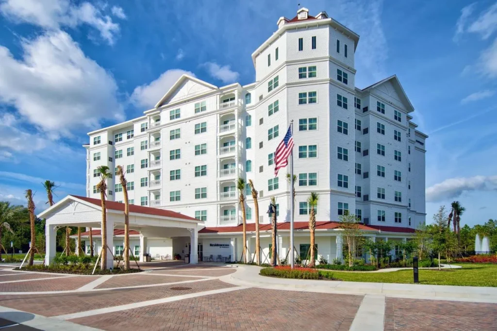 Exterior blanco de varios pisos y entrada cubierta del Residence Inn Orlando at Flamingo Crossings