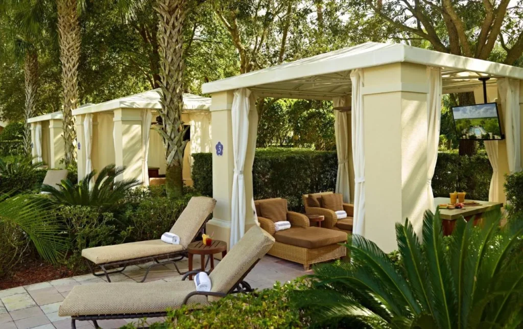 Cabañas blancas junto a la piscina con tumbonas entre palmeras en Omni Orlando Resort at ChampionsGate